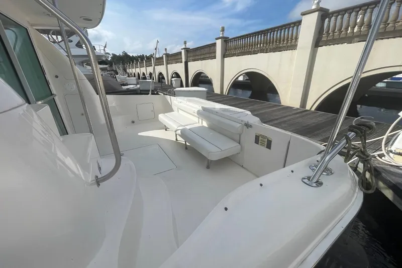 Slide: The Image of 1998 Sea Ray 480 Sedan Bridge yacht with spacious deck and seating, docked by a bridge. - 12