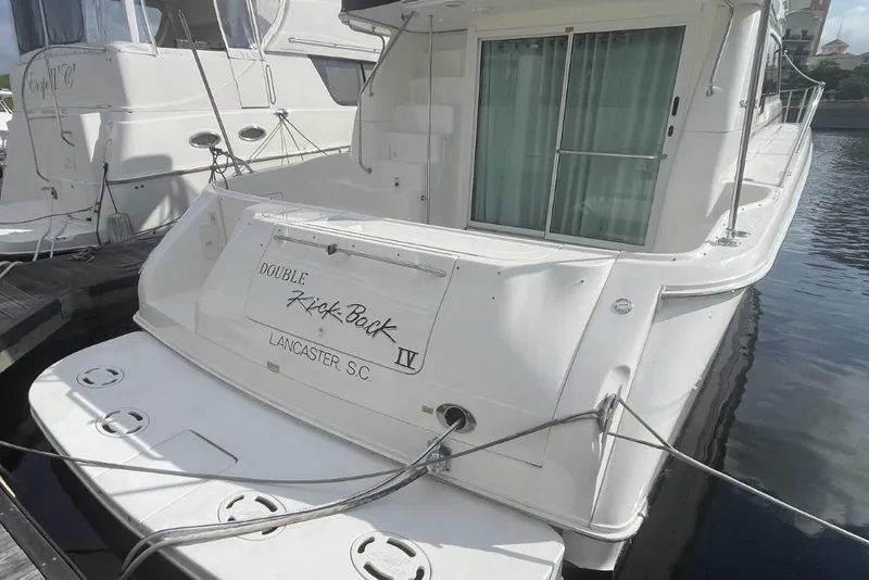 Slide: The Image of 1998 Sea Ray 480 Sedan Bridge yacht docked, rear view with "Double Kick Back" name. - 13