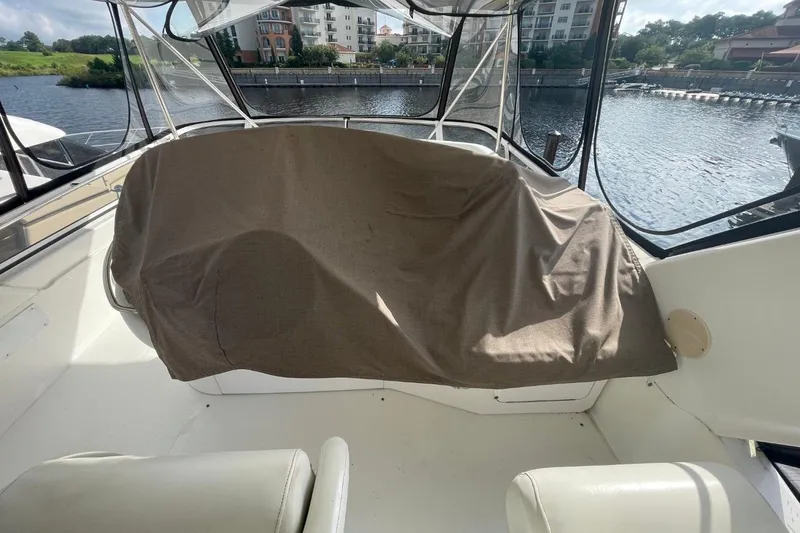 Slide: The Image of 1998 Sea Ray 480 Sedan Bridge interior with covered seating, overlooking marina and waterfront buildings. - 15
