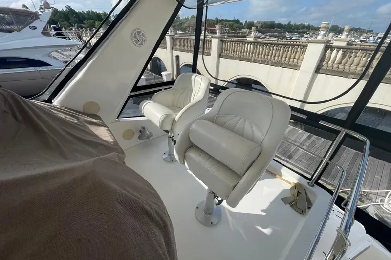 Slide: The Image of 1998 Sea Ray 480 Sedan Bridge interior with white leather seats at marina. - 18