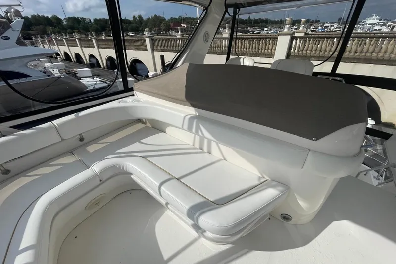 Slide: The Image of 1998 Sea Ray 480 Sedan Bridge interior with white seating and marina view. - 23