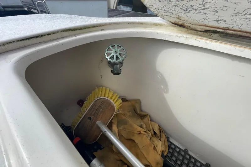 Slide: The Image of Storage compartment on a 1998 Sea Ray 480 Sedan Bridge with cleaning tools and faucet. - 31