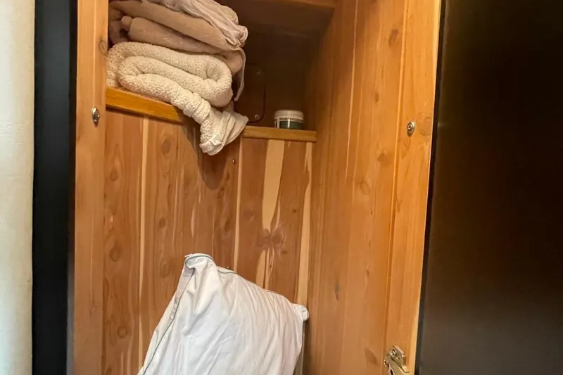 Slide: The Image of Wooden storage cabinet with folded towels and a pillow on a Sea Ray 480 Sedan Bridge. - 50