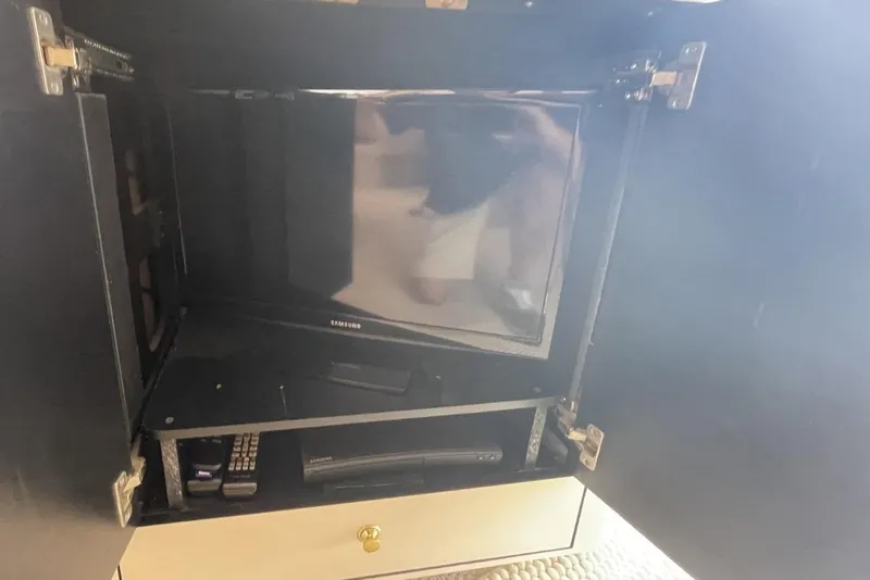 Slide: The Image of Cabinet with Samsung TV and remote controls on a 1998 Sea Ray 480 Sedan Bridge. - 63