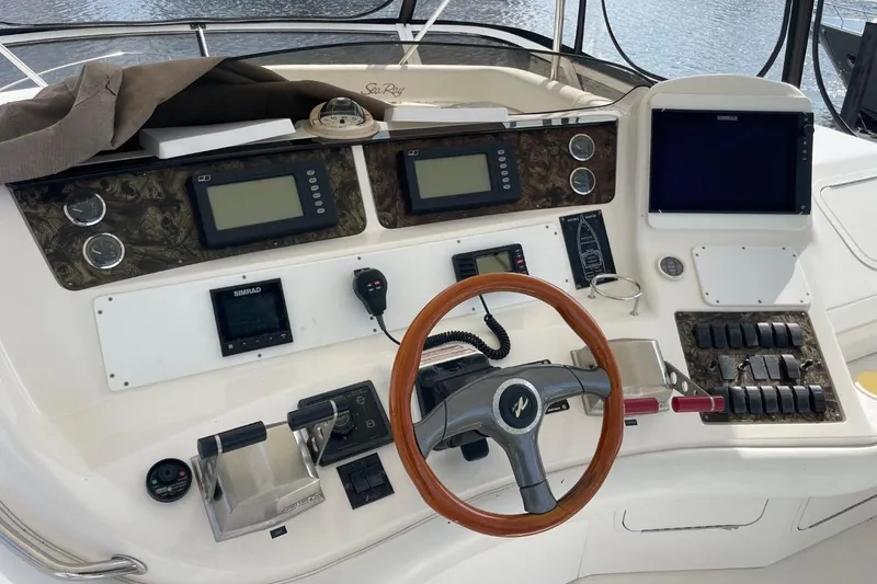Slide: The Image of 1998 Sea Ray 480 Sedan Bridge helm with navigation instruments and wooden steering wheel. - 75