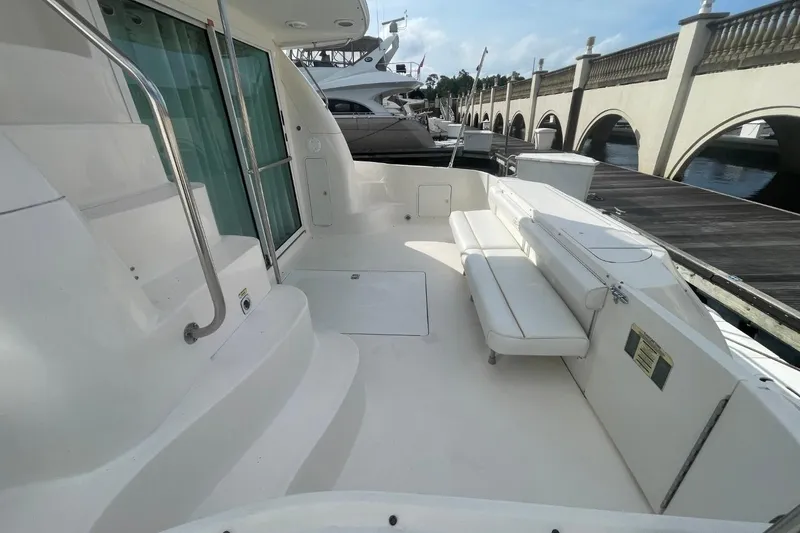 Slide: The Image of 1998 Sea Ray 480 Sedan Bridge yacht deck with seating, docked by a marina. - 9