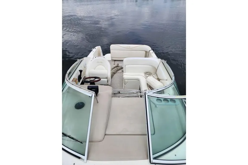 Slide: The Image of 2002 Sea Ray 260 Sundancer boat interior with white seating and steering wheel on calm water. - 10