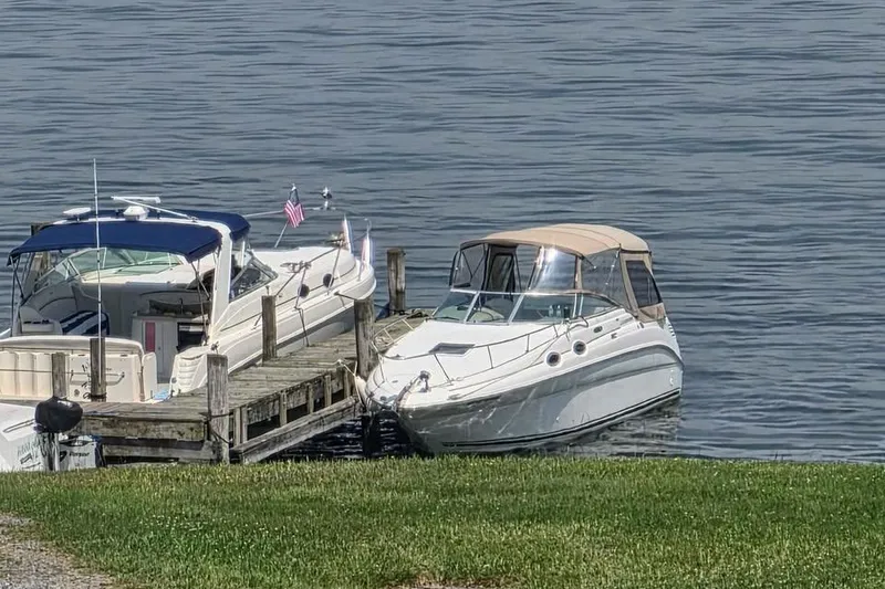 Slide: The Image of 2002 Sea Ray 260 Sundancer docked beside another boat on calm water. - 15