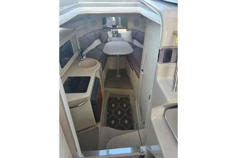 Slide: The Image of Interior of 2002 Sea Ray 260 Sundancer boat, featuring cozy seating and compact kitchenette. - 27