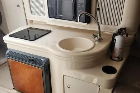 Slide: The Image of 2002 Sea Ray 260 Sundancer kitchenette with sink, stove, microwave, and fire extinguisher. - 33