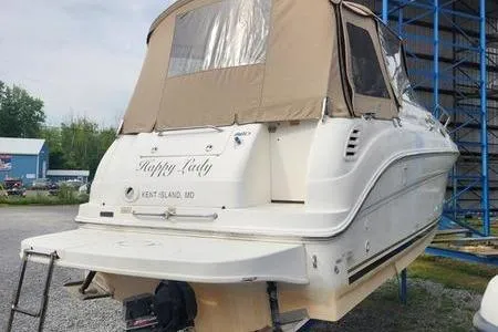 Slide: The Image of 2002 Sea Ray 260 Sundancer boat with beige canopy, docked on land. - 5