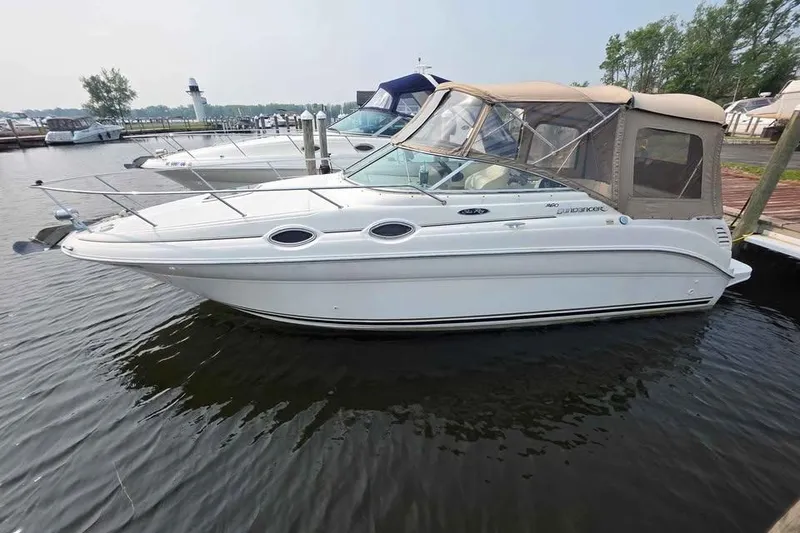 Slide: The Image of 2002 Sea Ray 260 Sundancer boat docked in marina, featuring sleek design and beige canopy. - 8