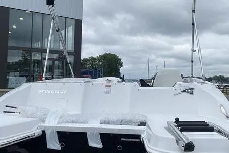 Slide: The Image of 2025 Stingray 182C boat docked near a modern building under cloudy skies. - 21
