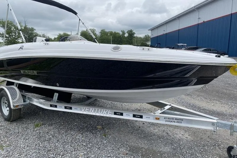 Slide: The Image of 2025 Stingray 182C boat on trailer, parked outdoors near a blue building. - 4