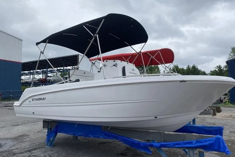 Slide: The Image of 2025 Stingray 173CC boat with canopy on trailer, overcast sky background. - 2