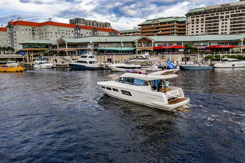 Slide: The Image of 2013 Prestige 500 Fly yacht cruising near a bustling waterfront with luxury buildings. - 5