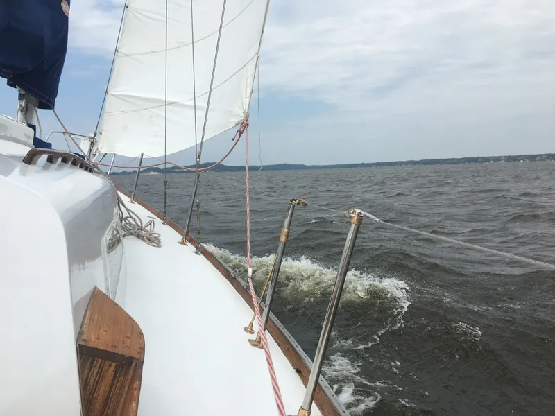 Slide: The Image of 1967 Islander 37 sailboat deck with wooden accents and winches, docked on calm water. - 17