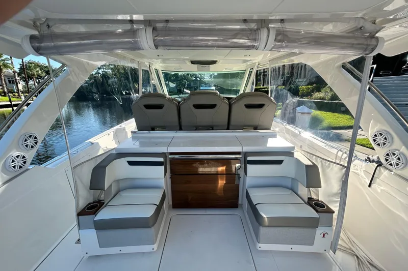 Slide: The Image of 2023 Tiara Yachts 38 LS interior with seating and helm, docked by a scenic waterway. - 15