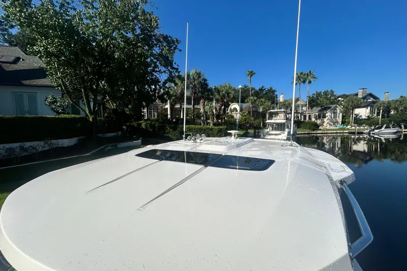 Slide: The Image of 2023 Tiara Yachts 38 LS on calm water, surrounded by lush greenery and luxury homes. - 49