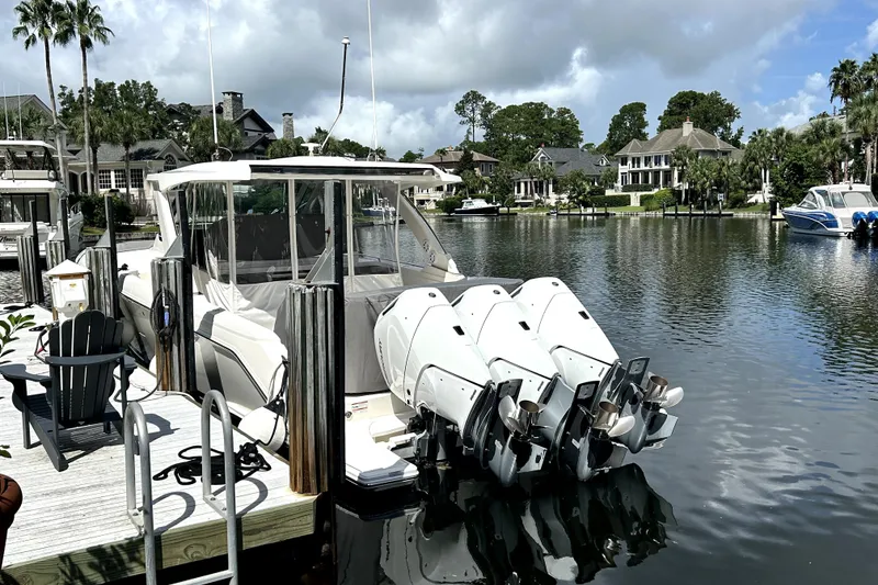 Slide: The Image of 2023 Tiara Yachts 38 LS docked by waterfront homes, featuring powerful outboard engines. - 8