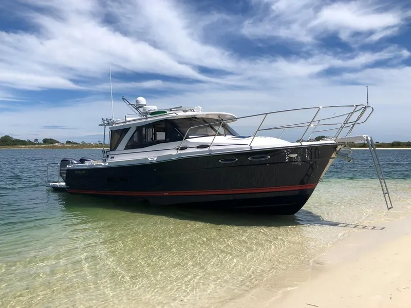 Slide: The Image of 2025 Cutwater C-32 Sedan boat on sandy shore under blue sky. - 2