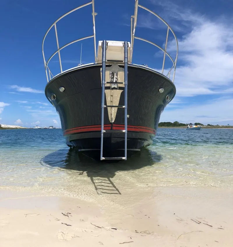 Slide: The Image of 2025 Cutwater C-32 Sedan boat beached on sandy shore with clear blue sky. - 6