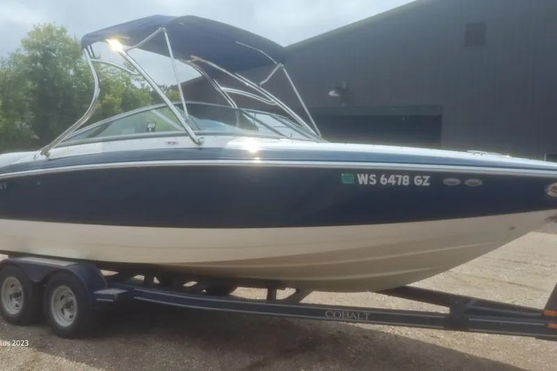Slide: The Image of 2006 Cobalt 240 boat on trailer, blue and white, parked outdoors. - 0