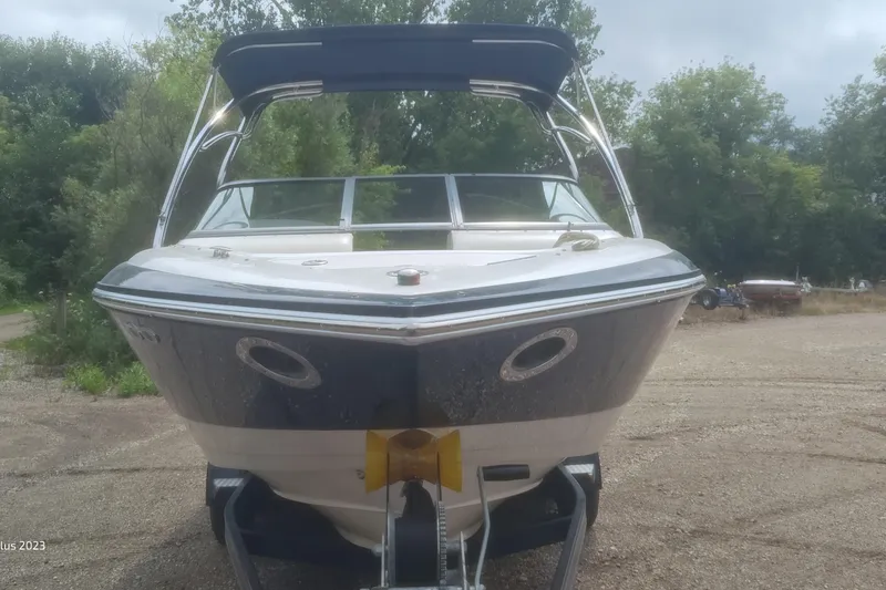 Slide: The Image of 2006 Cobalt 240 boat on trailer, parked outdoors with trees in background. - 2