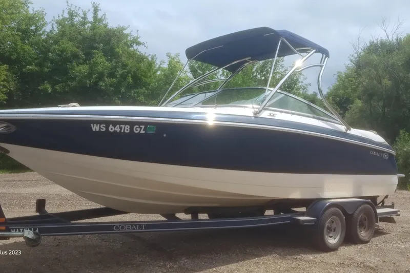 Slide: The Image of 2006 Cobalt 240 boat on trailer, parked outdoors with trees in background. - 4