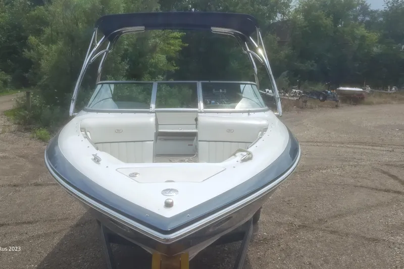 Slide: The Image of 2006 Cobalt 240 boat with open bow, parked on gravel, surrounded by trees. - 5