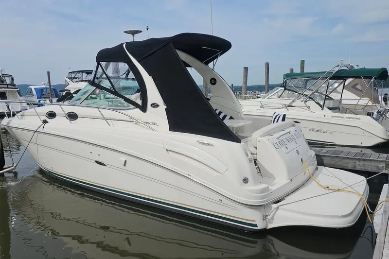 The Image of 2002 Sea Ray 300 Sundancer boat docked at marina, featuring sleek design and black canopy. - 0