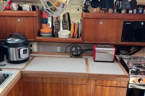 Slide: The Image of 1996 Hunter 376 yacht kitchen with wooden cabinets, appliances, and organized dishware. - 11