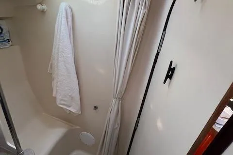 Slide: The Image of 1996 Hunter 376 yacht bathroom with shower, white towel, and curtain. - 15