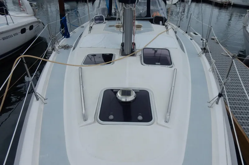 Slide: The Image of 1996 Hunter 376 sailboat deck view at marina, showcasing sleek design and hatches. - 27