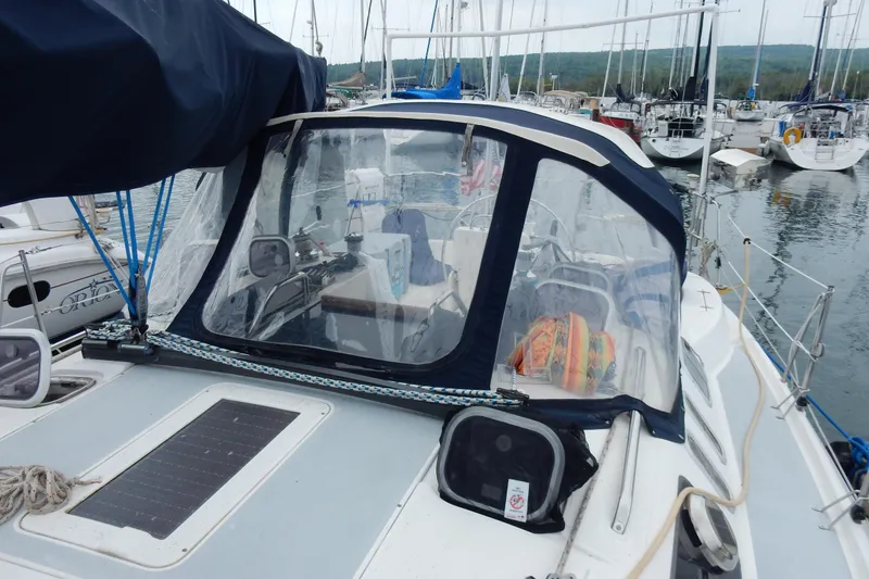 Slide: The Image of 1996 Hunter 376 sailboat docked in marina, featuring cockpit enclosure and nautical equipment. - 31