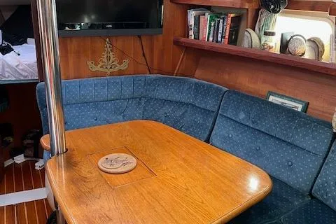 Slide: The Image of 1996 Hunter 376 yacht interior with blue seating, wooden table, and bookshelves. - 6
