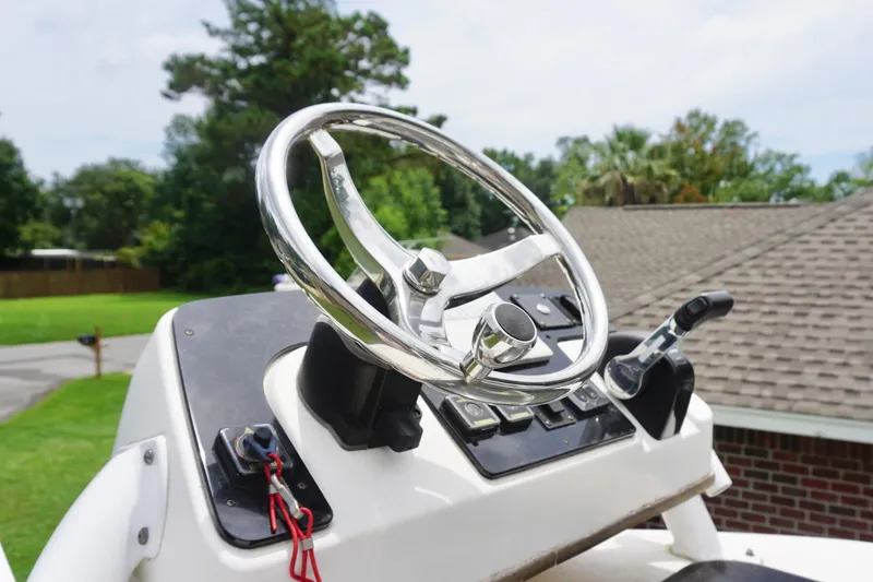 Slide: The Image of Steering wheel of 2019 Tidewater 2700 Carolina Bay boat, outdoors with trees in background. - 26