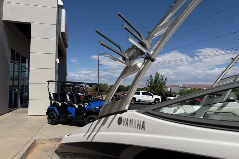 Slide: The Image of 2017 Yamaha AR190 boat near dealership, with golf cart and vehicles in background. - 17