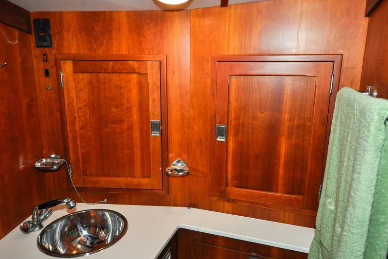 Slide: The Image of 1986 Hinckley Sou'wester 51 yacht bathroom with wooden cabinets and stainless steel sink. - 116