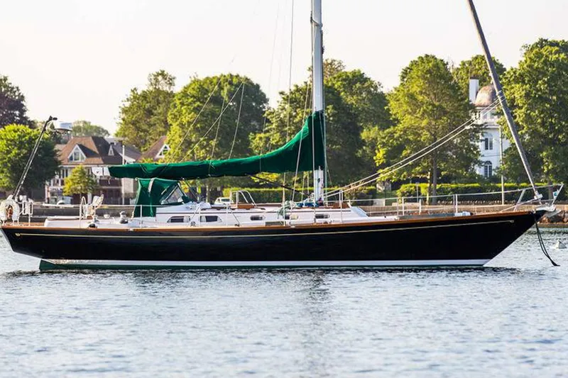 Slide: The Image of 1986 Hinckley Sou'wester 51 sailboat on calm water, surrounded by lush greenery. - 2