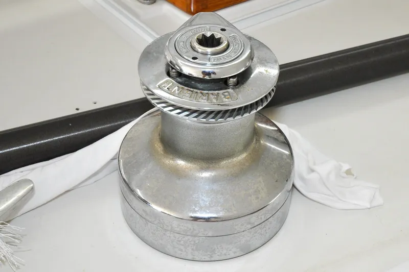 Slide: The Image of Chrome winch on 1986 Hinckley Sou'wester 51 sailboat deck, with rope and handle nearby. - 63
