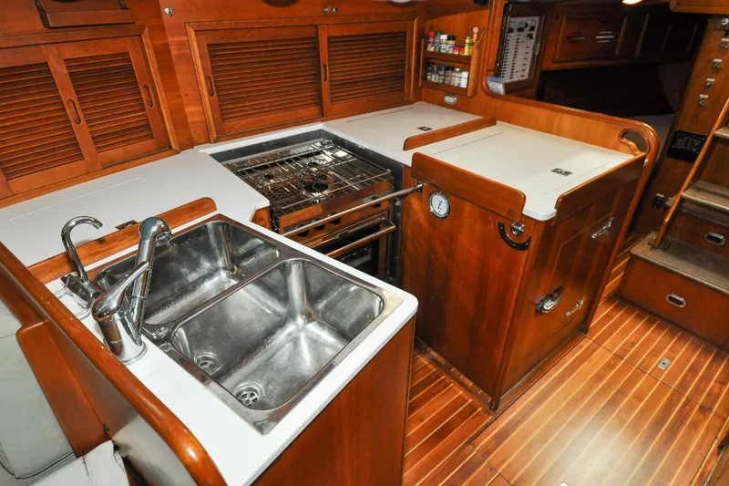 Slide: The Image of 1986 Hinckley Sou'wester 51 yacht kitchen with dual sinks, stove, and wooden cabinetry. - 98