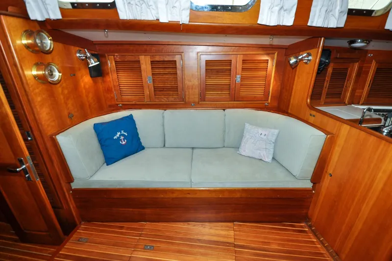 Slide: The Image of Cozy interior of 1986 Hinckley Sou'wester 51 sailboat with wooden finish and cushioned seating. - 103