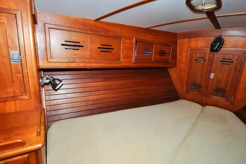 Slide: The Image of Hinckley Sou'wester 51 (1986) cabin interior with wooden paneling and cozy bed. - 111