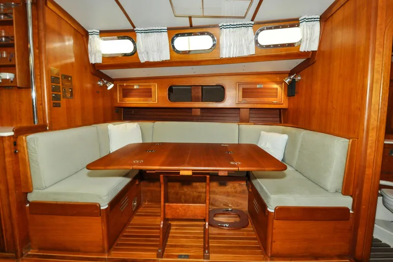 Slide: The Image of Interior of 1986 Hinckley Sou'wester 51 sailboat with wooden dining area and cushioned seating. - 121