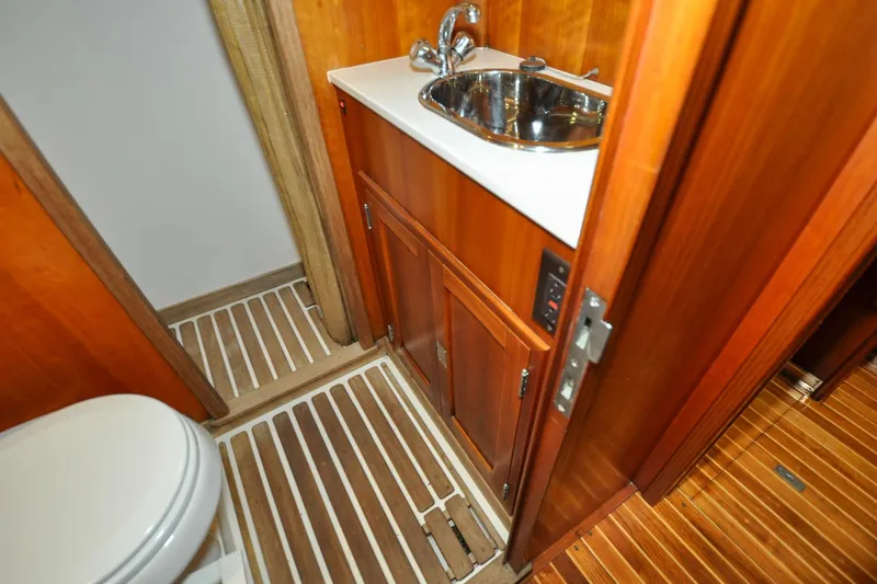Slide: The Image of Hinckley Sou'wester 51 yacht bathroom interior, featuring wooden cabinetry and stainless steel sink, 1986 model. - 129