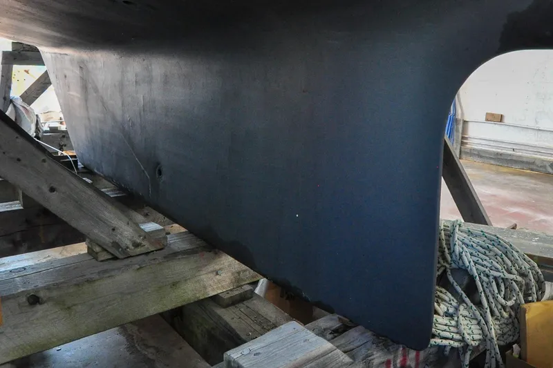 Slide: The Image of 1986 Hinckley Sou'wester 51 sailboat hull on wooden supports in a workshop. - 13