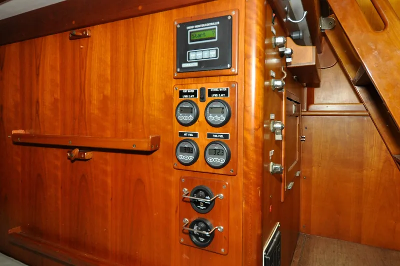 Slide: The Image of Hinckley Sou'wester 51 yacht interior control panel, 1986 model, featuring wooden cabinetry and gauges. - 76