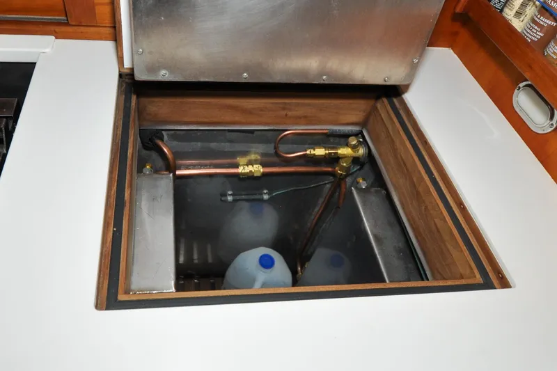 Slide: The Image of Hinckley Sou'wester 51 (1986) yacht interior storage compartment with plumbing and containers. - 90