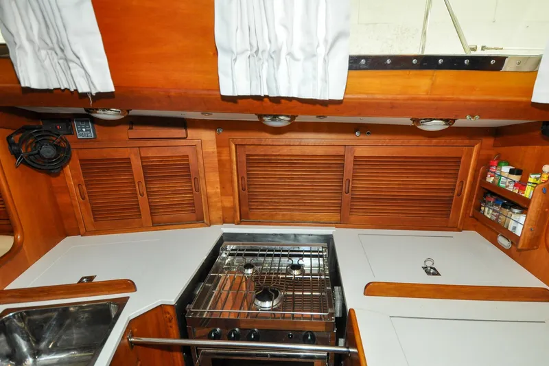 Slide: The Image of 1986 Hinckley Sou'wester 51 yacht kitchen with stove, wooden cabinets, and spice rack. - 93